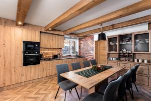 a kitchen and dining room with a wooden table and chairs at Chata Vlčia Skala - wellness in Heľpa
