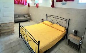 een slaapkamer met een bed met gele lakens en een bank bij Salento Calette Apartment in Santa Maria al Bagno