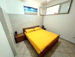 een slaapkamer met een bed met gele lakens en 2 ramen bij Salento Calette Apartment in Santa Maria al Bagno