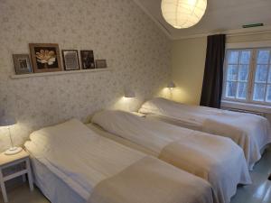 two beds in a bedroom with two lamps and a window at Brobacka Gästhem in Jomala