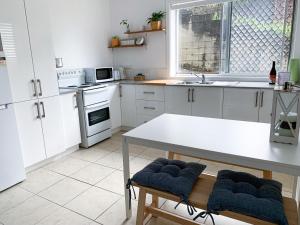 a kitchen with white cabinets and a white table at Cooly Coastal Escape walk to beach & shops in Gold Coast