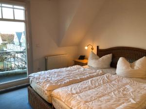 a bedroom with a bed with white sheets and a window at Stromstr_2 _Boddenblick_ Whg_26 in Zingst