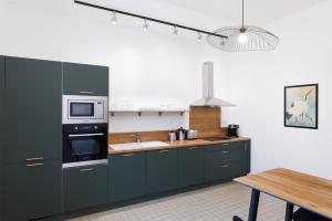 a kitchen with green cabinets and a microwave and a table at La Pittoresque 1 in Carcassonne