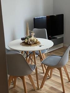 une table à manger blanche avec des chaises et une télévision dans l'établissement Baltic Sea Apartments, à Gdańsk