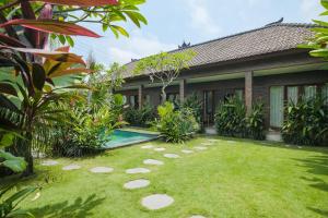 a garden with a swimming pool in front of a house at The Kumpi Bali by The Lavana in Canggu