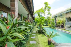 a garden with a swimming pool next to a building at The Kumpi Bali by The Lavana in Canggu