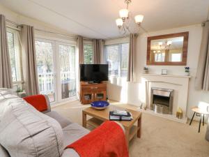 a living room with a couch and a tv at Manderine Lodge in Morpeth