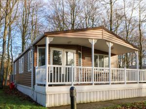 a tiny house with a wrap around porch at Manderine Lodge in Morpeth