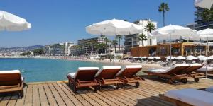a deck with chairs and umbrellas on a beach at LE CONSTELLATION AP4333 By Riviera Holiday Homes in Juan-les-Pins