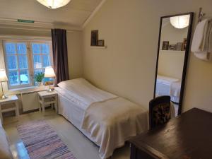 a bedroom with a bed and a mirror and a table at Brobacka Gästhem in Jomala