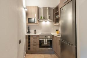 uma pequena cozinha com armários de madeira e um frigorífico de aço inoxidável em El Racó em Camprodon