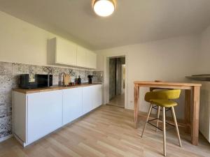 a kitchen with a table and a yellow stool at Großzügige FeWo mit Bergblick am Tegernsee in Bad Wiessee