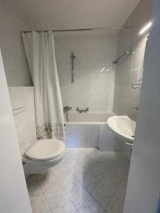 a bathroom with a toilet and a tub and a sink at Großzügige FeWo mit Bergblick am Tegernsee in Bad Wiessee