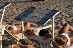 un grupo de personas tumbadas en sillas de jardín en la playa en Hotel Sogaris, en Paestum