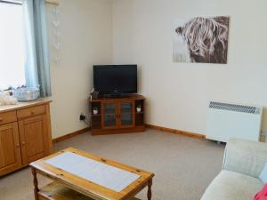 sala de estar con TV y mesa de centro en Acorn Cottage en Cononbridge
