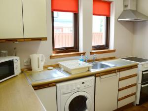a kitchen with a sink and a washing machine at Acorn Cottage in Cononbridge