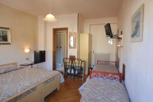 1 dormitorio con 2 camas, mesa y TV en Hotel Elena, en Stresa
