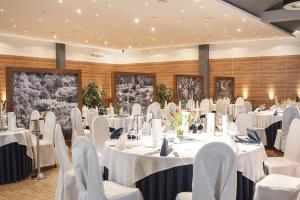 - une salle de banquet avec des tables et des chaises blanches dans l'établissement Hotel Eden, à Rzgów