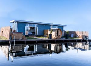 une maison bleue avec un quai à côté d'une masse d'eau dans l'établissement Proosdij B055A, à Vinkeveen