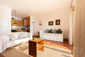 a living room with a white couch and a table at Surf- Com vista para o Oceano in São Martinho do Porto