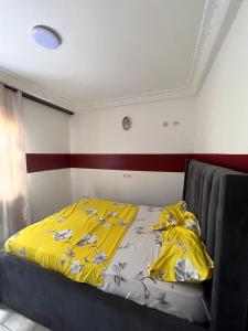 a bedroom with a bed with a yellow blanket at Appartement New Stading YAOUNDE - MIMBOMAN MAETURE in Yaoundé