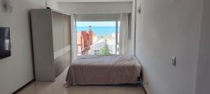 a bedroom with a bed and a large window at Departamento in Puerto Madryn