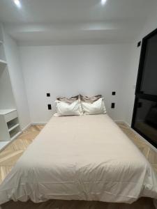 een groot wit bed in een kamer met een tv bij Les Trois Cyprès in Blois
