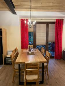 comedor con mesa de madera y cortinas rojas en Apartament Franio, en Jaworki