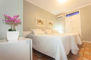 1 dormitorio con 1 cama y un jarrón con flores rosas en Hotel Belo Horizonte, en Natal