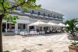 a hotel with tables and umbrellas in a courtyard at Danai Hotel & Spa in Olympic Beach