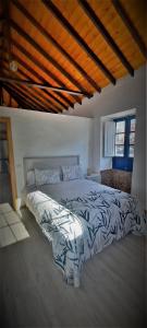 a bedroom with a bed with a black and white comforter at Casa Higopico in Tacoronte