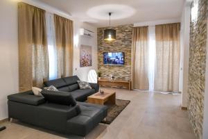 sala de estar con sofá negro y TV en Villa Isabella, en Opatija