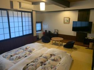 1 dormitorio con cama, mesa y TV de pantalla plana en Koyado Enn, en Toyooka