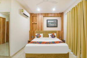 a bedroom with a large bed with yellow curtains at FabHotel The Nawab's in Nalmatha