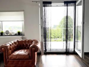 ein Ledersofa im Wohnzimmer mit großem Fenster in der Unterkunft Amazing & design 2-room apartment near Cologne in Trompete