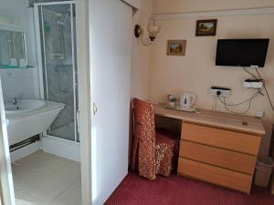 een badkamer met een wastafel en een bureau met een televisie bij Diamond House in Rugby