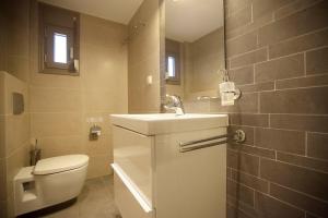 a bathroom with a white toilet and a sink at Ammouda Villas in Ormos Panagias +37 photos