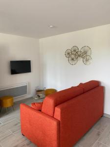 a living room with a red couch and a tv at Bienvenue au Pâtis Colas ! in Mesvres