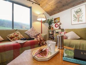 una sala de estar con sofás y una mesa con un plato de comida en The Badger's Shack, en Kendal 22 fotos más