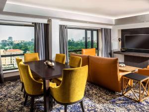 ラゴスにあるMövenpick Hotel Ikoyi Lagosのダイニングテーブルと椅子が備わるホテルルームです。