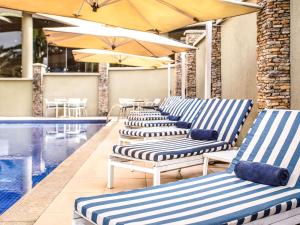 a row of lounge chairs next to a swimming pool at Mövenpick Hotel Ikoyi Lagos in Lagos