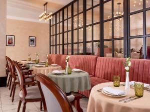 タシュケントにあるMercure Tashkentのテーブルと赤いソファのあるレストラン