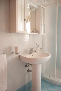 La salle de bains blanche est pourvue d'un lavabo et d'un miroir. dans l'établissement Sotza’s Little House, à Padru