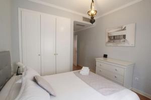 a white bedroom with a bed and a dresser at Sevilla Clásica: amigos y familia. Parking gratis! in Seville