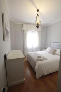 a white bedroom with a bed and a window at Sevilla Clásica: amigos y familia. Parking gratis! in Seville