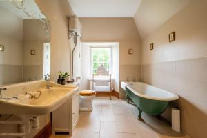 y baño con 2 lavabos, bañera y aseo. en Assynt House 5 Star Exclusive Use Venue, en Dingwall