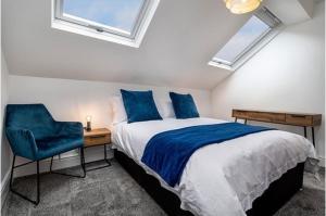 a bedroom with a bed with a desk and a blue chair at Oakdene in Deganwy