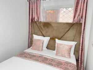 a bed with two pillows and a window at Chambre moderne avec cuisine à Bonamoussadi (Kotto) in Douala