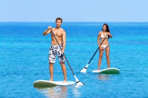 a man and a woman on paddle boards in the water at Danat Jebel Dhanna Resort in Jebel Dhanna