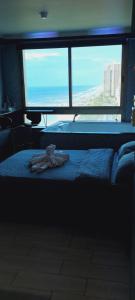 a bed with a stuffed animal on it in front of a window at מלון כרמל/מגדל C in Netanya